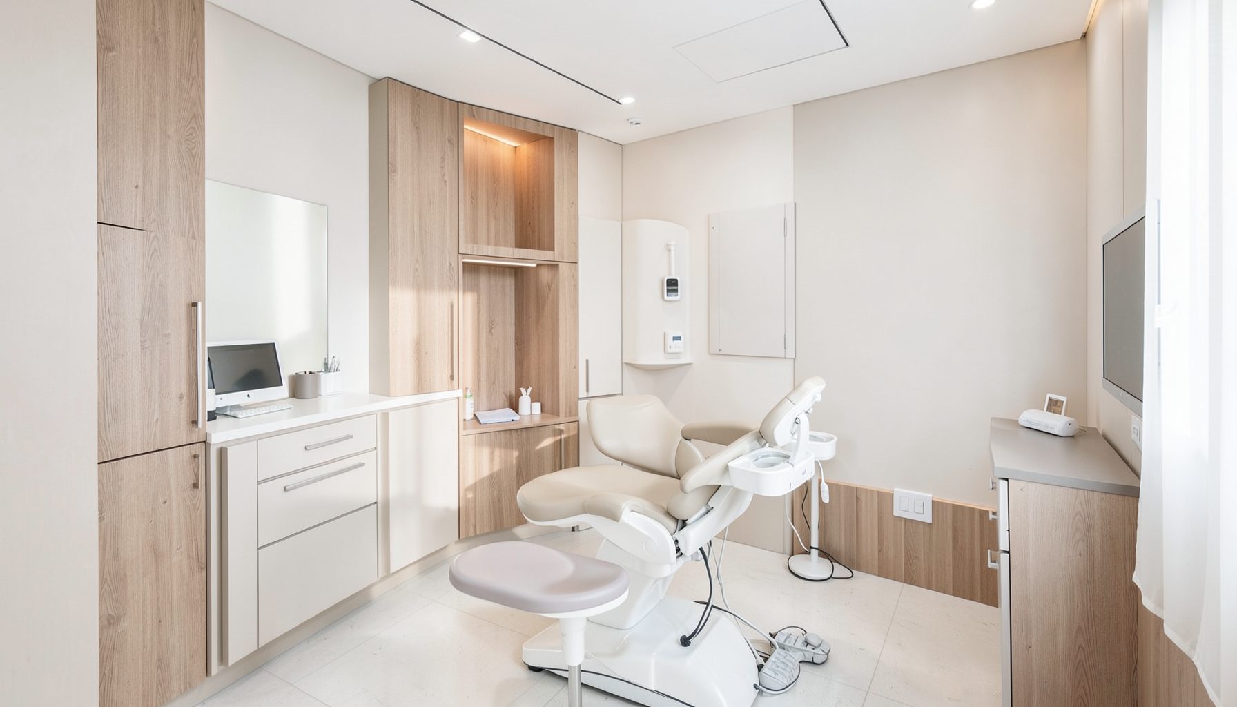 Aydınlık ve modern bir diş kliniği ortamı; yumuşak beyaz ve açık gri tonlarında, sıcak ahşap detaylarla dengelenmiş, ferah bir tedavi odası atmosferi.